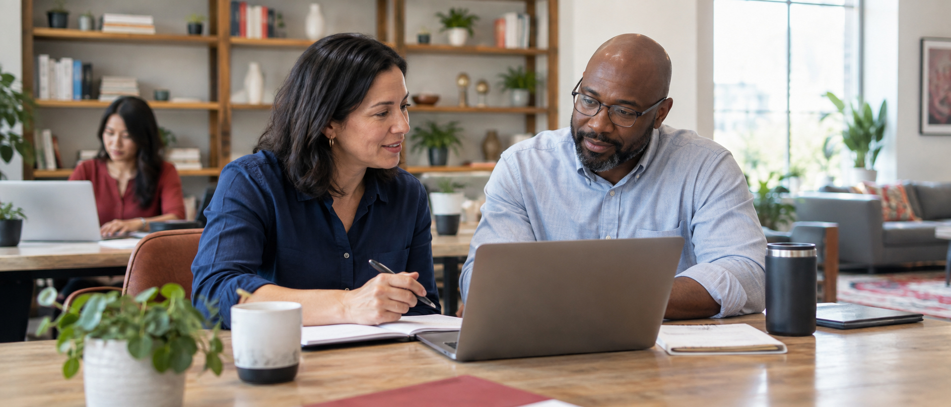 Two coworkers reviewing compensation planning notes together at a desk.