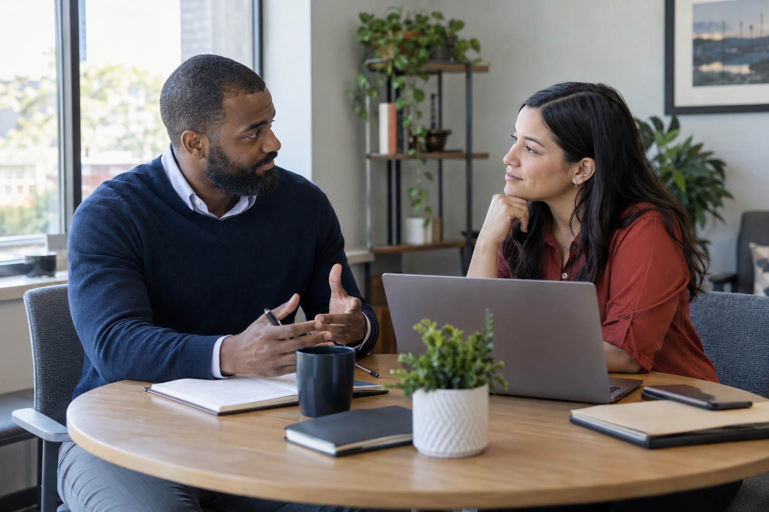 Two professionals having a focused conversation over a laptop.